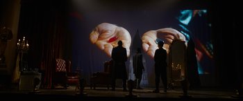 Movie still from “The Matrix Resurrections” (2021), directed by Lana Wachowski – Two men standing in front of a projection screen; Wide shot, Low angle