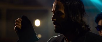 Movie still from “The Matrix Resurrections” (2021), directed by Lana Wachowski – A person with long hair and a beard; Close Up shot, Over the shoulder angle