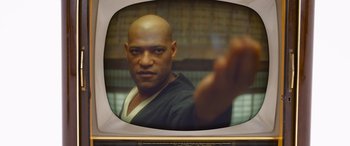 Movie still from “The Matrix Resurrections” (2021), directed by Lana Wachowski – A man with a shaved head is holding his hand out to the camera; Close Up shot, Over the shoulder angle