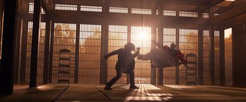 Movie still from “The Matrix Resurrections” (2021), directed by Lana Wachowski – A man is doing a kick in a cage; Wide shot, Low angle