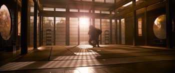 Movie still from “The Matrix Resurrections” (2021), directed by Lana Wachowski – A man kneeling down in the middle of an indoor area; Extreme Wide shot, Low angle