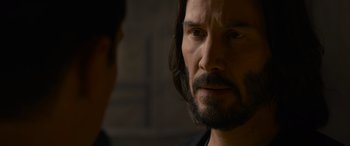 Movie still from “The Matrix Resurrections” (2021), directed by Lana Wachowski – A person with a beard; Close Up shot, Over the shoulder angle