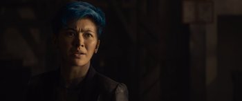 Movie still from “The Matrix Resurrections” (2021), directed by Lana Wachowski – A woman with blue hair is standing in the dark; Close Up shot, Over the shoulder angle
