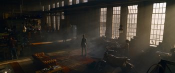 Movie still from “The Matrix Resurrections” (2021), directed by Lana Wachowski – A person standing in a room with a motorcycle; Extreme Wide shot, High angle
