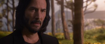 Movie still from “The Matrix Resurrections” (2021), directed by Lana Wachowski – A man with long black hair and a beard; Close Up shot, Over the shoulder angle