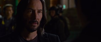 Movie still from “The Matrix Resurrections” (2021), directed by Lana Wachowski – A man with long black hair is looking at the camera; Close Up shot, Over the shoulder angle