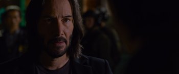 Movie still from “The Matrix Resurrections” (2021), directed by Lana Wachowski – A person with long hair and a beard; Close Up shot, Over the shoulder angle