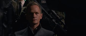 Movie still from “The Matrix Resurrections” (2021), directed by Lana Wachowski – A man in a suit and a gun; Close Up shot, Over the shoulder angle