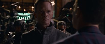 Movie still from “The Matrix Resurrections” (2021), directed by Lana Wachowski – A man that is standing in front of a crowd; Close Up shot, Over the shoulder angle