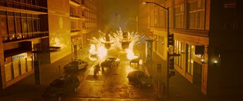 Movie still from “The Matrix Resurrections” (2021), directed by Lana Wachowski – A street scene with cars on fire and a person standing on the sidewalk; Extreme Wide shot, High angle