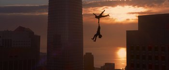 Movie still from “The Matrix Resurrections” (2021), directed by Lana Wachowski – A man is hanging upside down in the air while a woman is hanging upside down in front of a tall building; Extreme Wide shot, Low angle
