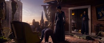 Movie still from “The Matrix Resurrections” (2021), directed by Lana Wachowski – A woman standing on the floor of a room with a man kneeling on the ground; Wide shot, Over the shoulder angle