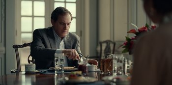 Movie still from “Dopesick” (2021), directed by Danny Strong – A man sitting at a table with food in front of him; Medium shot, Over the shoulder angle