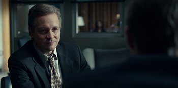 Movie still from “Dopesick” (2021), directed by Danny Strong – A man wearing a suit and tie sitting in front of another man in a suit; Close Up shot, Over the shoulder angle
