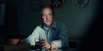 Movie still from “Dopesick” (2021), directed by Danny Strong – A man sitting at a table holding a glass of wine; Close Up shot, Low angle