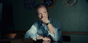 Movie still from “Dopesick” (2021), directed by Danny Strong – A man sitting at a table with a drink in front of him; Close Up shot, Low angle