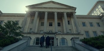 Movie still from “Dopesick” (2021), directed by Danny Strong – Two men are walking down the steps of a building; Extreme Wide shot, Low angle