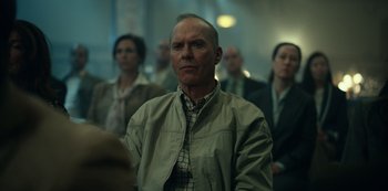 Movie still from “Dopesick” (2021), directed by Danny Strong – An older man is standing in front of a group of people; Medium shot, Low angle