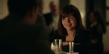 Movie still from “Dopesick” (2021), directed by Danny Strong – A woman sitting at a table with a glass in front of her face; Close Up shot, Over the shoulder angle