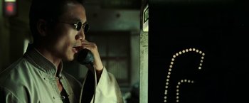 Movie still from “The Matrix Revolutions” (2003), directed by Lilly Wachowski – A man talking on a phone while wearing sunglasses; Close Up shot, Low angle