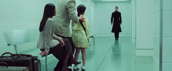 Movie still from “The Matrix Revolutions” (2003), directed by Lilly Wachowski – A group of people standing in a room with a man in a black coat; Wide shot, Over the shoulder angle