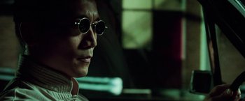 Movie still from “The Matrix Revolutions” (2003), directed by Lilly Wachowski – A man wearing round sunglasses and a white shirt; Close Up shot, Low angle