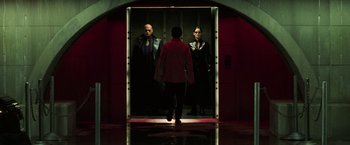 Movie still from “The Matrix Revolutions” (2003), directed by Lilly Wachowski – A man and two women are walking in front of a mirror; Wide shot, Low angle