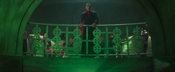 Movie still from “The Matrix Revolutions” (2003), directed by Lilly Wachowski – A man standing on top of a green railing next to a crowd of onlookers; Wide shot, Low angle