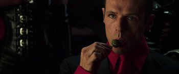 Movie still from “The Matrix Revolutions” (2003), directed by Lilly Wachowski – A man in a red shirt and black jacket eating a piece of food; Close Up shot, Low angle