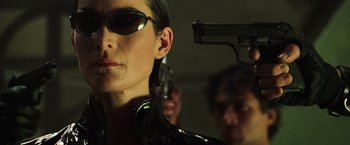 Movie still from “The Matrix Revolutions” (2003), directed by Lilly Wachowski – A woman in a leather jacket holding a gun; Close Up shot, Low angle