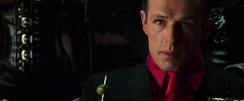 Movie still from “The Matrix Revolutions” (2003), directed by Lilly Wachowski – A person wearing a suit and tie; Close Up shot, Over the shoulder angle
