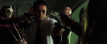 Movie still from “The Matrix Revolutions” (2003), directed by Lilly Wachowski – A man holding a gun while another man holds a gun; Medium shot, Low angle