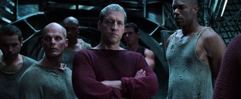 Movie still from “The Matrix Revolutions” (2003), directed by Lilly Wachowski – A man with his arms crossed standing in front of other men; Medium shot, Low angle