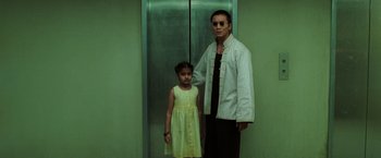 Movie still from “The Matrix Revolutions” (2003), directed by Lilly Wachowski – A man standing next to a little girl in front of an elevator; Medium shot, Low angle