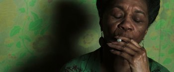 Movie still from “The Matrix Revolutions” (2003), directed by Lilly Wachowski – A woman is smoking a cigarette in a dark room; Close Up shot, Low angle