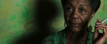 Movie still from “The Matrix Revolutions” (2003), directed by Lilly Wachowski – An older woman wearing a green shirt and earrings; Close Up shot, Low angle