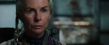 Movie still from “The Matrix Revolutions” (2003), directed by Lilly Wachowski – An older woman wearing a necklace and looking at the camera; Close Up shot, Over the shoulder angle