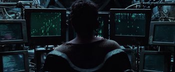 Movie still from “The Matrix Revolutions” (2003), directed by Lilly Wachowski – A man sitting in front of three computer monitors; Medium shot, High angle