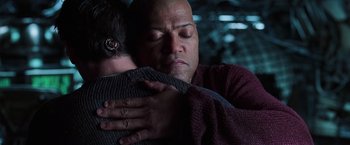 Movie still from “The Matrix Revolutions” (2003), directed by Lilly Wachowski – A man holding a young child in his arms; Close Up shot, Over the shoulder angle