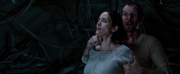 Movie still from “The Matrix Revolutions” (2003), directed by Lilly Wachowski – A man and a woman are standing in a dark room; Close Up shot, Over the shoulder angle