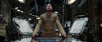 Movie still from “The Matrix Revolutions” (2003), directed by Lilly Wachowski – A man standing in front of a glass table; Medium shot, Low angle
