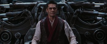 Movie still from “The Matrix Revolutions” (2003), directed by Lilly Wachowski – A man wearing a red scarf and a white shirt is sitting in a chair; Medium shot, High angle