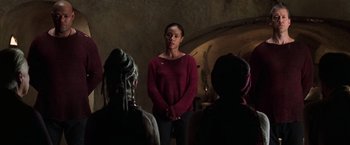 Movie still from “The Matrix Revolutions” (2003), directed by Lilly Wachowski – A group of people sitting in front of each other in a room; Medium shot, Over the shoulder angle