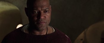 Movie still from “The Matrix Revolutions” (2003), directed by Lilly Wachowski – A bald man wearing a sweater stares into the camera; Close Up shot, Low angle