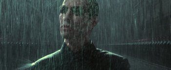 Movie still from “The Matrix Revolutions” (2003), directed by Lilly Wachowski – A man in a black shirt is standing in the rain; Close Up shot, Low angle