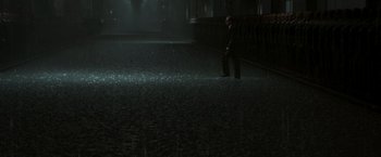 Movie still from “The Matrix Revolutions” (2003), directed by Lilly Wachowski – A man in a suit and tie standing in a dark room; Extreme Wide shot, High angle