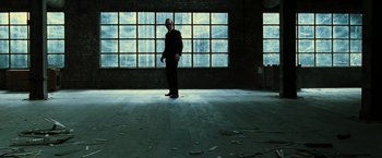 Movie still from “The Matrix Revolutions” (2003), directed by Lilly Wachowski – A man standing in front of large windows in a room; Wide shot, Low angle