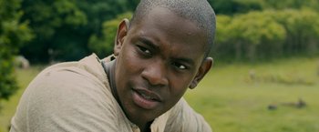 Movie still from “The Maze Runner” (2014), directed by Wes Ball – A man's face with trees in the background; Close Up shot, High angle