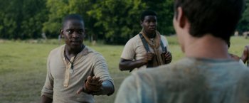 Movie still from “The Maze Runner” (2014), directed by Wes Ball – A group of men standing on top of a grass covered field; Medium shot, Over the shoulder angle