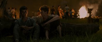 Movie still from “The Maze Runner” (2014), directed by Wes Ball – A man sitting on top of a tree stump; Medium shot, Over the shoulder angle